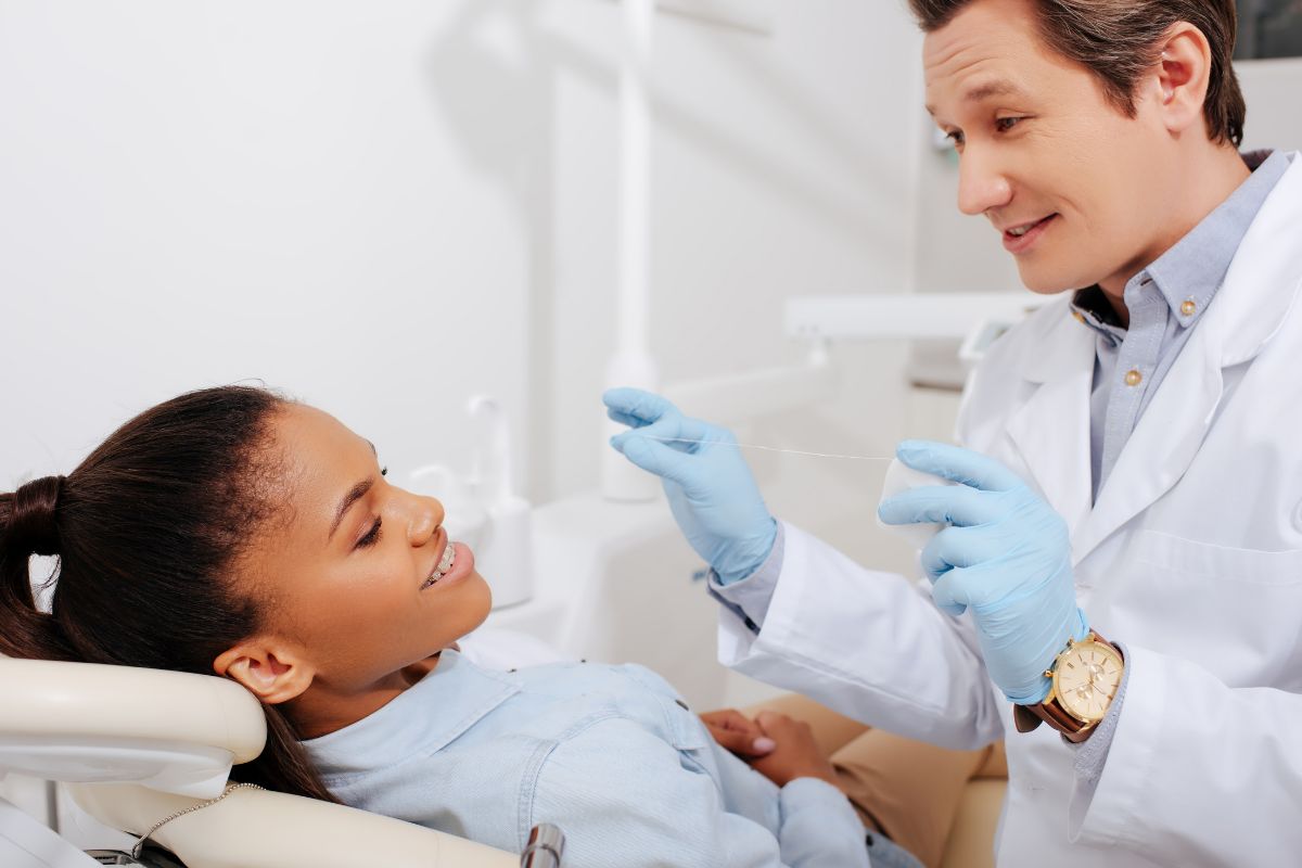 Dentist examines young patient's teeth in clinical office setting wearing protective gloves.